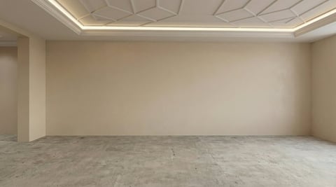 Empty modern room with beige walls, polished concrete floor, and geometric ceiling with ambient lighting